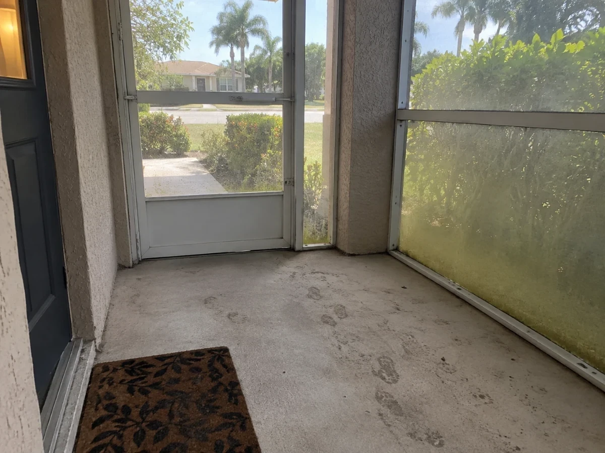 A screened entry porch floor with tracked dust and a light pollen film on the screening.